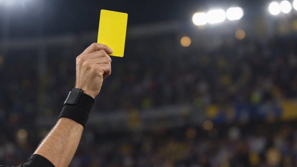 Árbitro levantando cartão amarelo durante uma partida
