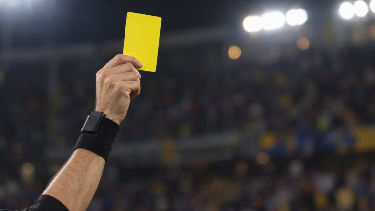 Árbitro levantando cartão amarelo durante uma partida