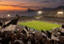 Arquibancada lotada com bandeiras pretas e brancas em noite de jogo em Natal