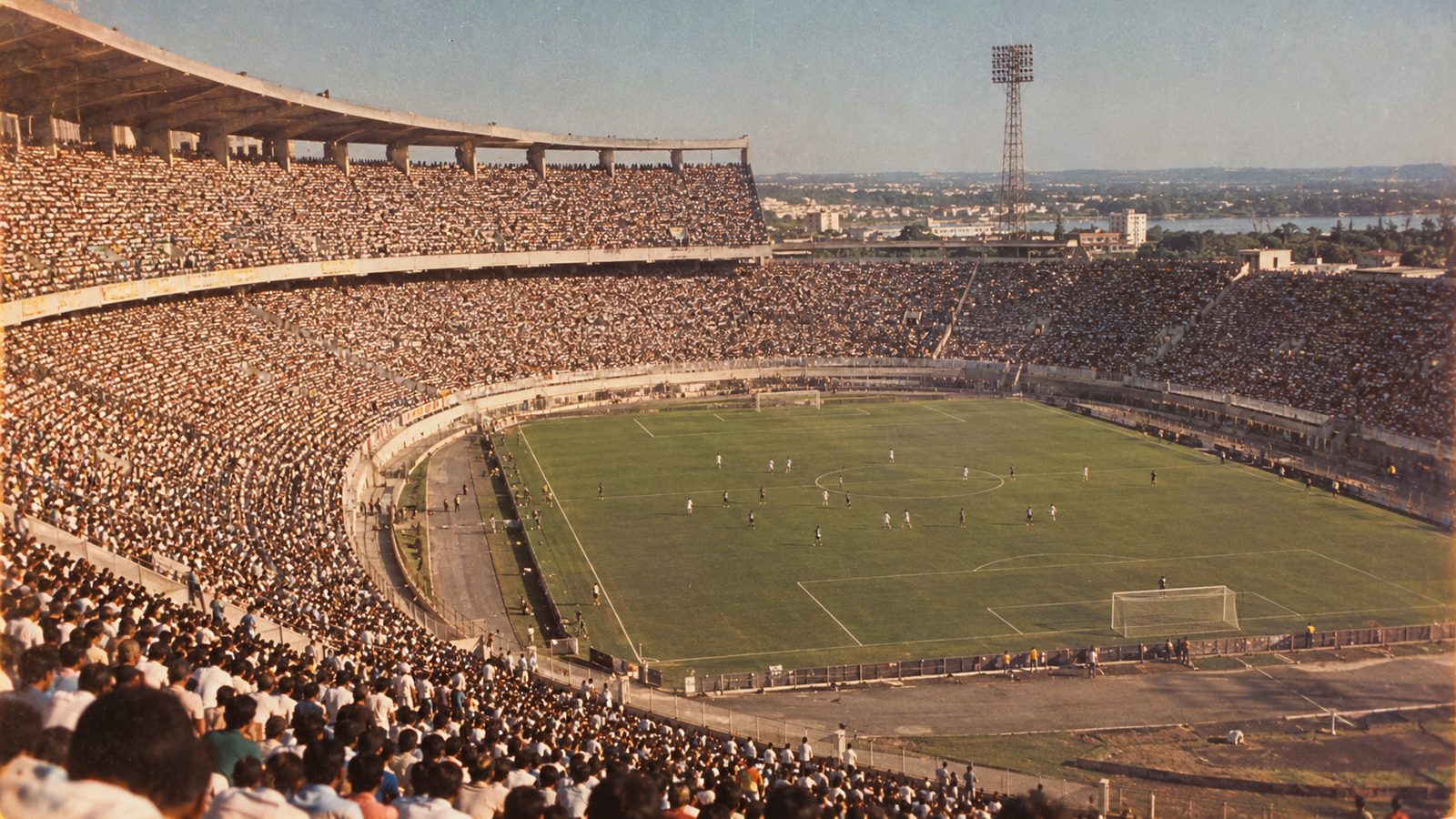 Multidão lotando arquibancadas de concreto em estilo de foto dos anos 1970